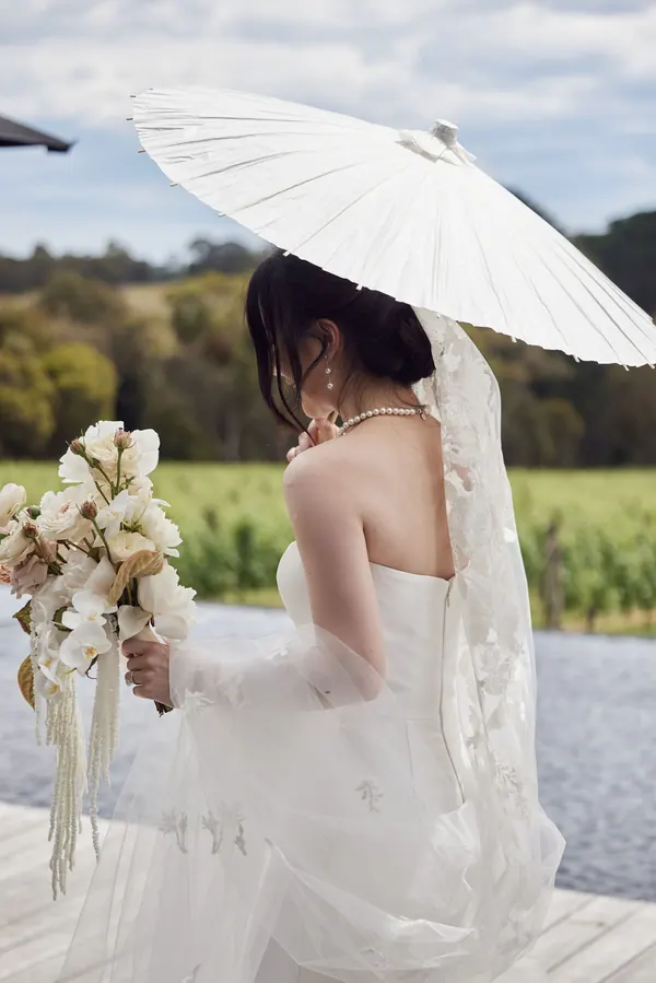 Under a white parasol at a vineyard, dark hair worn up